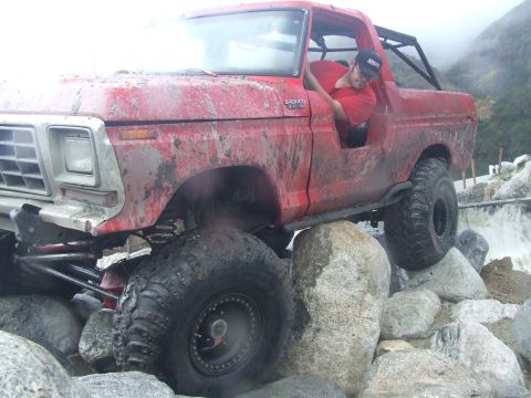 1978 Ford Bronco - A driver maneuvers a red 1978 Ford Bronco over a rocky obstacle course.