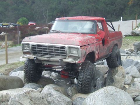 1978 Ford Bronco - This red 1978 Ford Bronco is shown tackling a challenging rocky terrain, demonstrating its off-road capabilities.