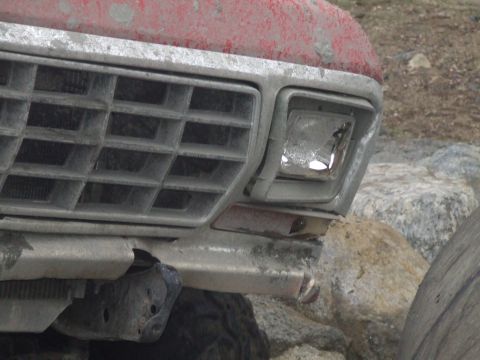 1978 Ford Bronco - Close-up of the front grille and damaged headlight of a 1978 Ford Bronco.