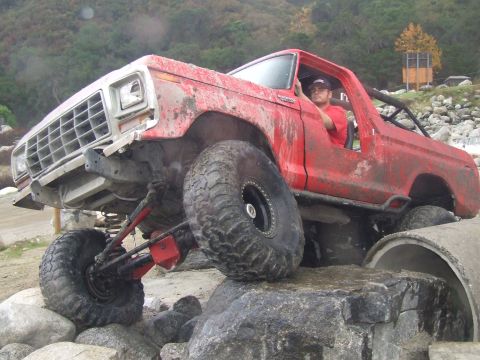 1978 Ford Bronco - A red 1978 Ford Bronco navigates a challenging off-road course with large tires and a lifted suspension.