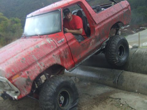1978 Ford Bronco - This red 1978 Ford Bronco is shown navigating an off-road obstacle course, driving over large concrete pipes.