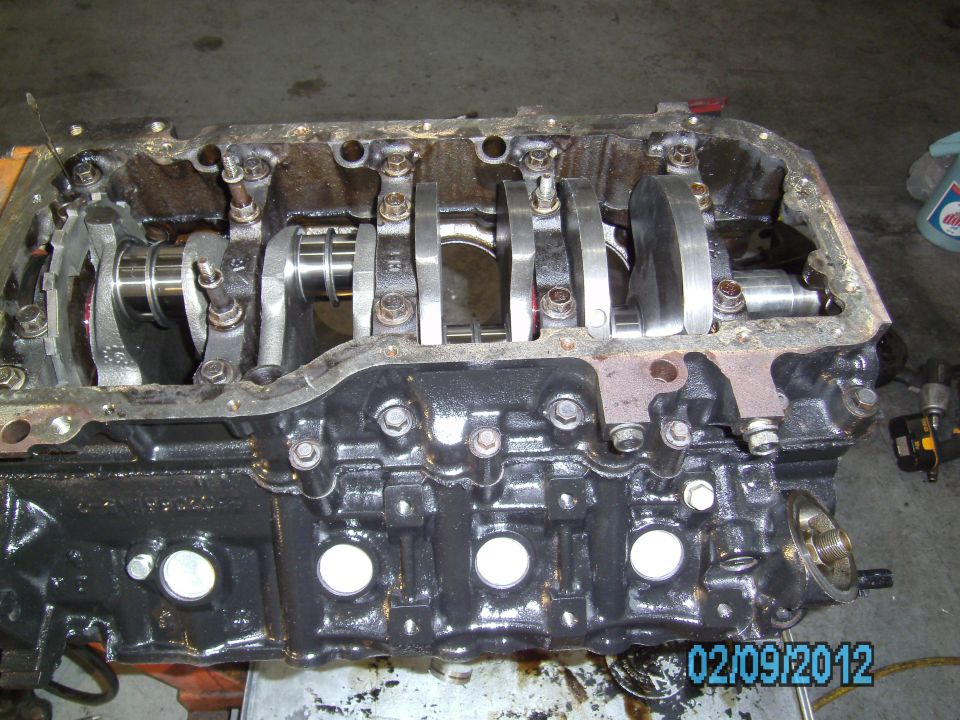 Engine block with crankshaft and connecting rods visible. Oil pan removed