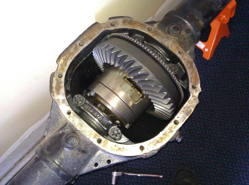 Differential housing with exposed ring and pinion gears, showing wear and a socket wrench nearby