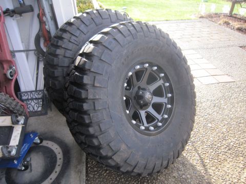 2008 Jeep Wrangler - Two large off-road tires with aggressive tread patterns and black multi-spoke rims are shown.