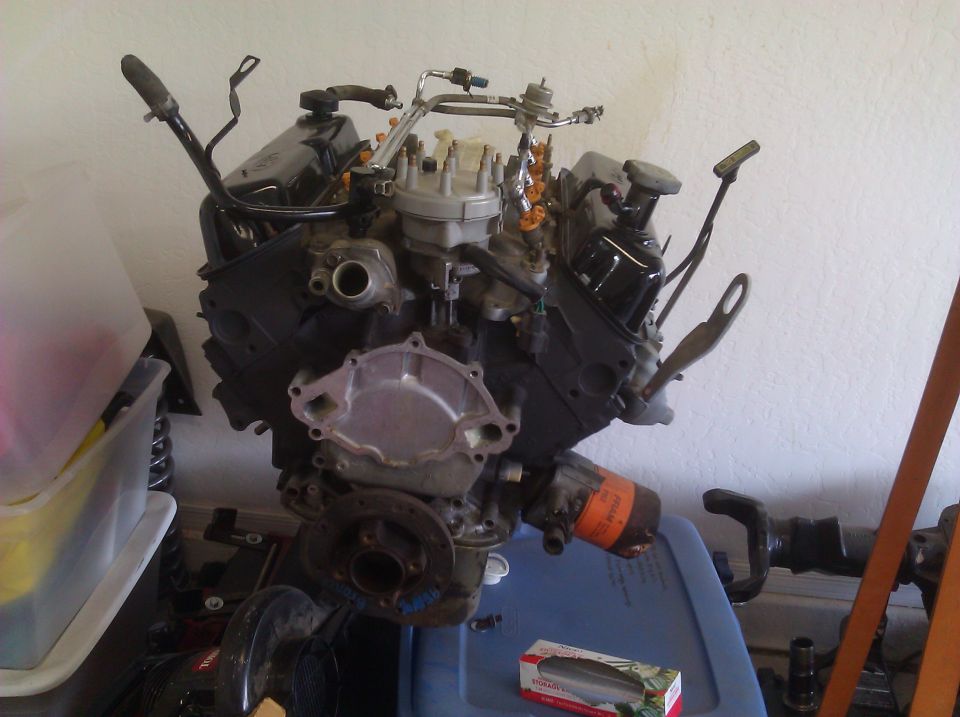 Engine block with fuel lines, oil filter, and distributor cap. Some parts are black, others silver