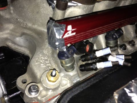1988 Ford Bronco - Close-up view of engine components including fuel injectors and spark plugs, with a red fuel rail.