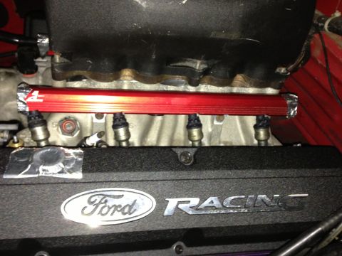 1988 Ford Bronco - Close-up of a red fuel rail and a black valve cover with Ford Racing branding.