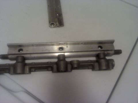 1995 Ford Probe - A metal fuel rail with visible injector ports is shown on a flat surface.