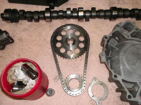 1971 Ford Ranchero - Engine timing components including a camshaft, timing chain, sprockets, and lifters are arranged on a surface.