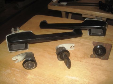 1993 Ford Bronco - Several vehicle door handles and lock cylinders are laid out on a wooden table.