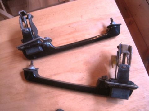 1993 Ford Bronco - Two black door handles with visible metal mechanisms are displayed on a wooden surface.