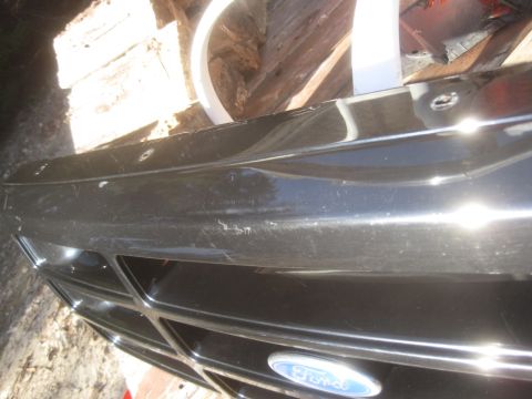 1993 Ford Bronco - Close-up of a black Ford Bronco grille, showing a dented section above the emblem.