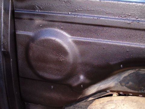 1990 Ford Bronco - Underside of a vehicle showing textured undercoating and a molded circular detail.