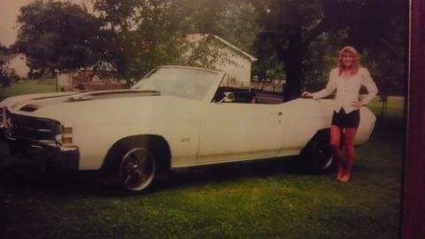 1989 Ford Bronco - A woman stands next to a white 1970 Chevrolet Chevelle SS convertible parked on grass.