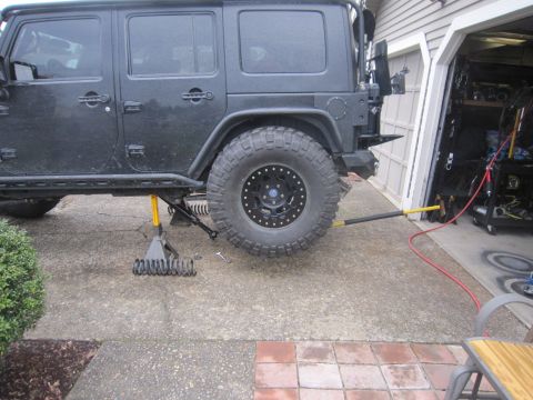 2008 Jeep Wrangler - A black Jeep Wrangler is elevated on jack stands, indicating maintenance or repair work is underway in the driveway.
