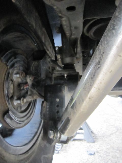 2008 Jeep Wrangler - Close-up view of the vehicle's undercarriage reveals modified suspension parts and a large shock absorber.