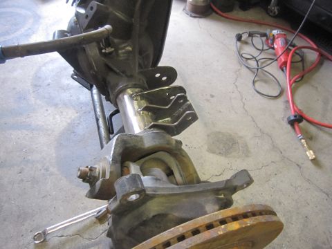 2008 Jeep Wrangler - A Jeep Dana 44 front axle assembly is shown with a brake rotor and an air tool on the concrete floor.