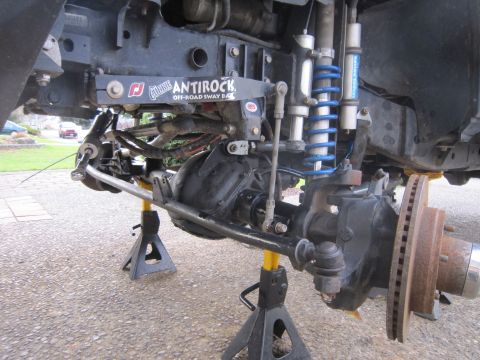2008 Jeep Wrangler - Close-up of a vehicle's suspension system, an Antirock off-road sway bar, with the vehicle elevated on jack stands.