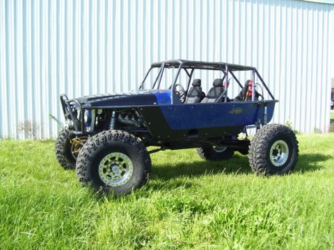 1967 Ford Mustang - Custom off-road buggy with large tires and roll cage sits on grass in front of a building.