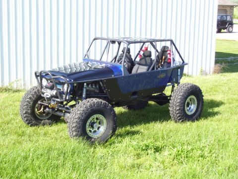 1967 Ford Mustang - A custom-built off-road buggy with a roll cage and large tires is parked on a grassy lawn next to a building.