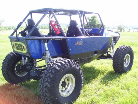 1967 Ford Mustang - This custom buggy features a blue body, roll cage, and oversized off-road tires, seen from the rear.