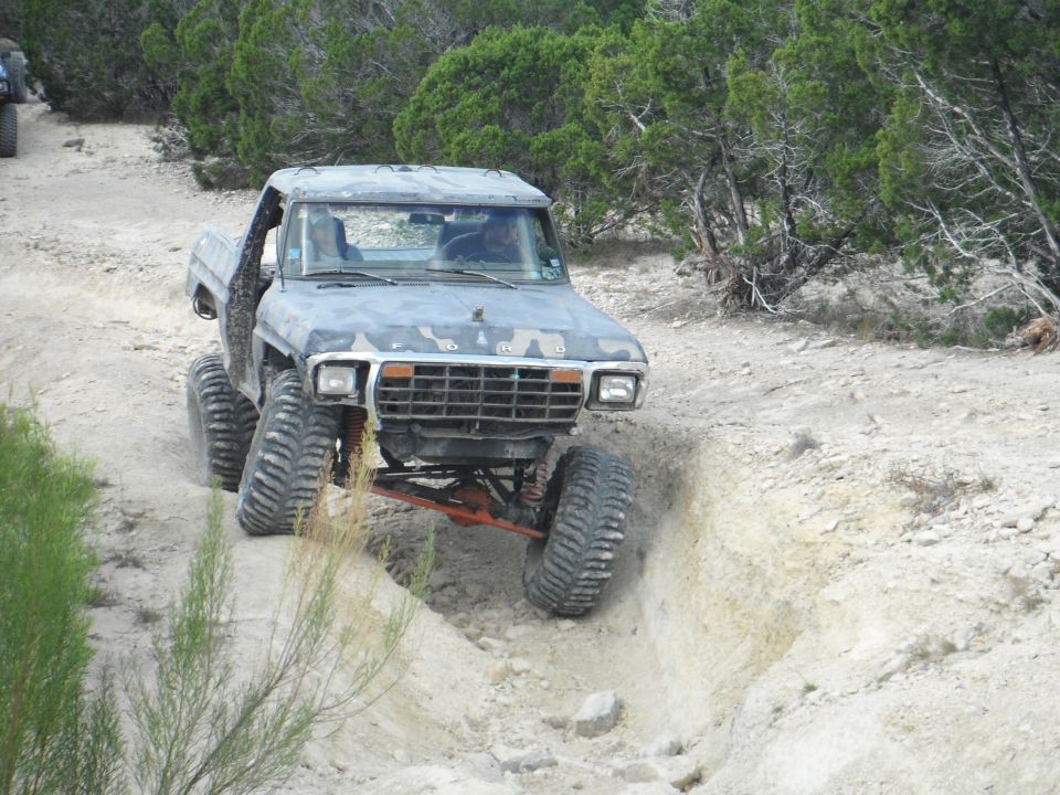 Modified 1979 Ford Bronco climbing a dirt trail with large tires