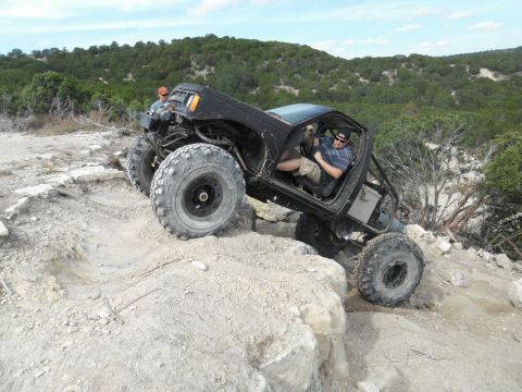 1979 Ford Bronco - Modified off-road vehicle tackling a challenging rocky trail with two occupants.