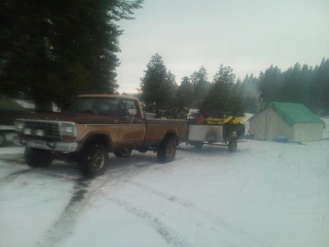 1979 Ford F-150 - Brown 1979 Ford F-150 pickup truck parked in the snow, towing a trailer with an ATV and camping equipment.