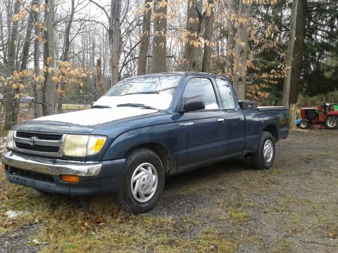 1978 Ford F-150 - A blue Toyota Tacoma pickup truck is parked in a wooded area with a light dusting of snow on its hood.