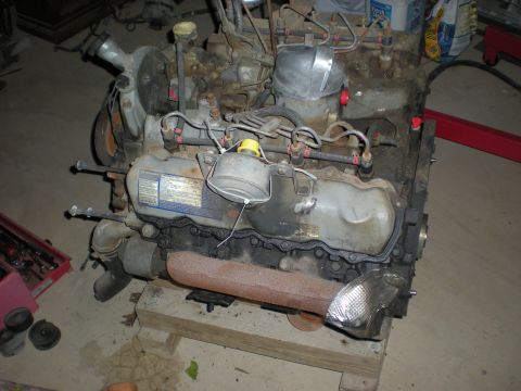 1986 Ford Bronco - A diesel engine is shown, resting on wooden blocks in what appears to be a garage or workshop.