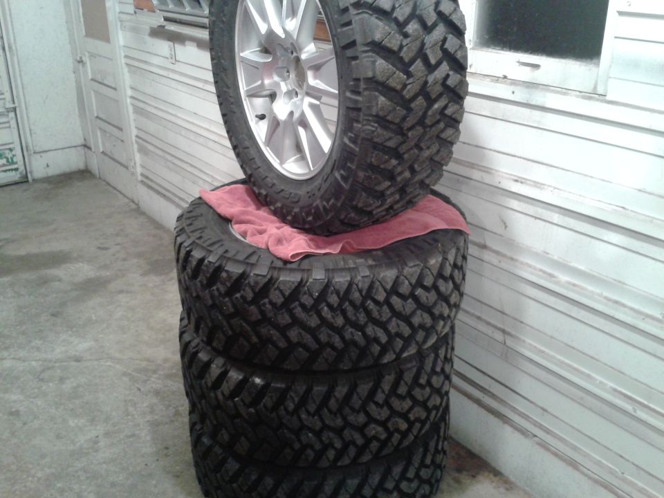 Stack of four off-road tires, one with a silver rim
