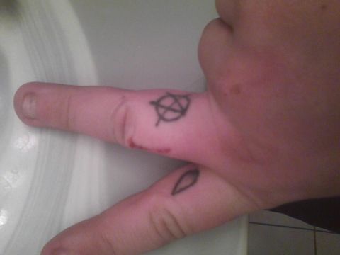 2003 Ford Crown Victoria - A hand displays tattoos of an anarchy symbol and a leaf on its fingers.