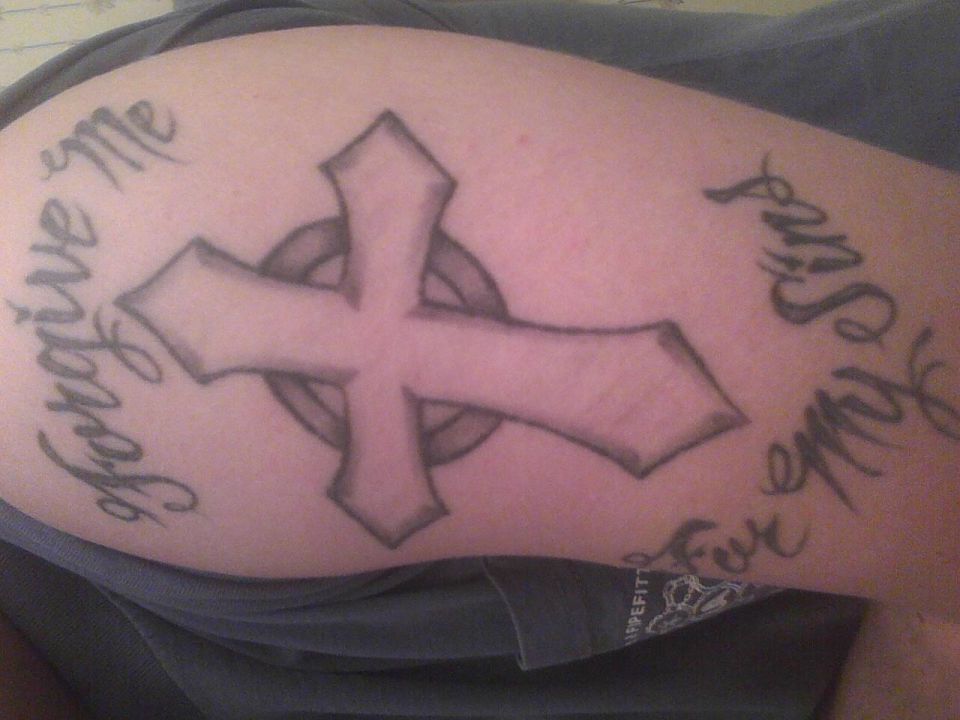 Tattoo of a cross with text 'Forgive me for all my sins' on skin