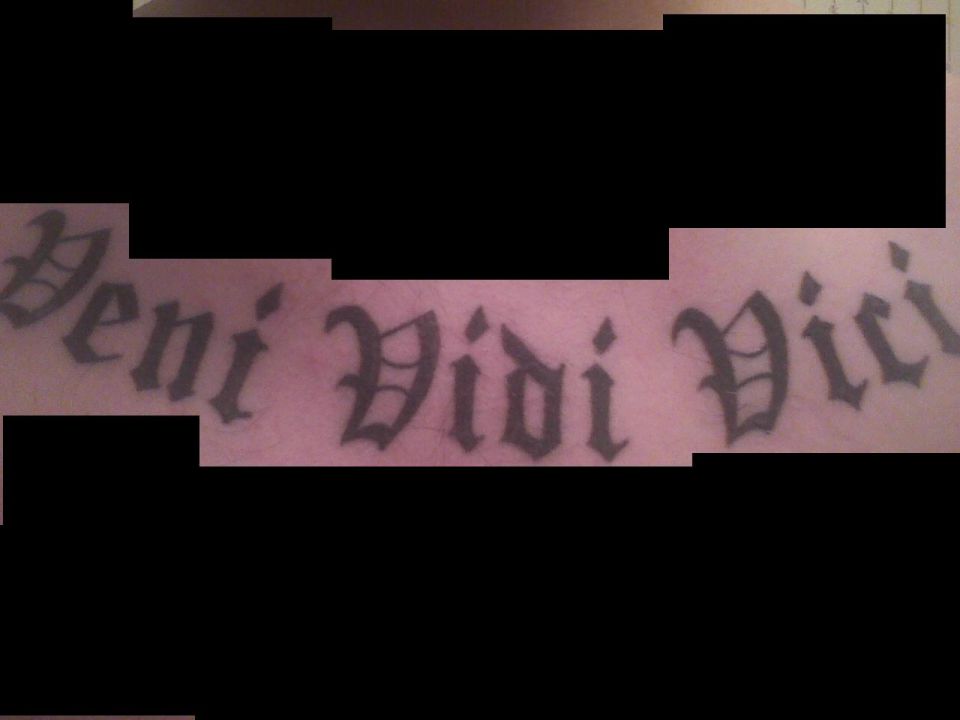 Tattoo text reading 'Veni Vidi Vici' in gothic script