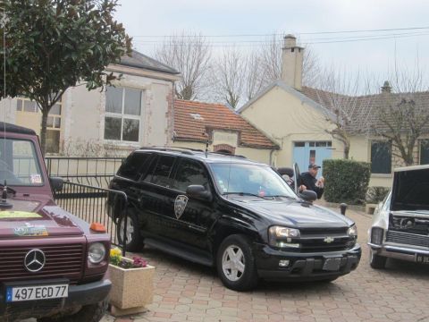 1991 Ford LTD Crown Victoria - A black SUV, possibly a police vehicle, is parked alongside other vehicles in a courtyard.