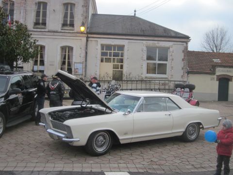 1991 Ford LTD Crown Victoria - A white coupe with its hood open is parked next to a black SUV, with several people observing.