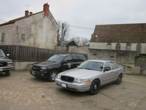 1991 Ford LTD Crown Victoria - A silver Ford Crown Victoria sedan is parked in front of old buildings, with other vehicles nearby.