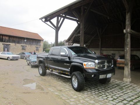 1991 Ford LTD Crown Victoria - Black Dodge Ram 1500 pickup truck parked outdoors near a rustic building with other vehicles present.