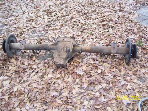 1990 Ford Bronco - A rusty rear axle assembly is shown resting on a bed of dry leaves.