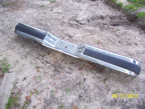 1990 Ford Bronco - A chrome bumper with black rubber trim is shown on the ground.