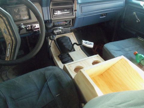1985 Ford Bronco - The interior of this 1985 Ford Bronco features a custom-built wooden center console with cup holders and a CB radio.