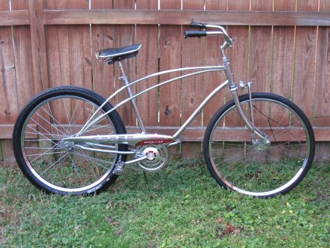 1994 Ford Bronco - A shiny cruiser bicycle with a distinctive frame design is shown against a wooden fence backdrop.