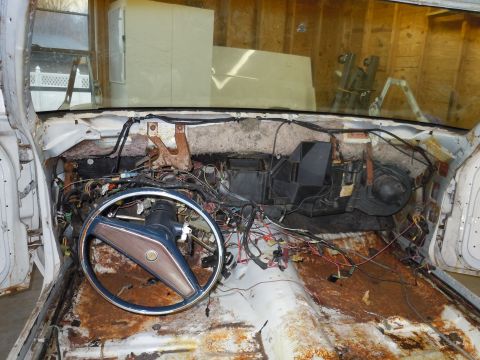 2001 Ford Crown Victoria - The interior of a car is shown with its dashboard removed, revealing extensive wiring and rust damage.