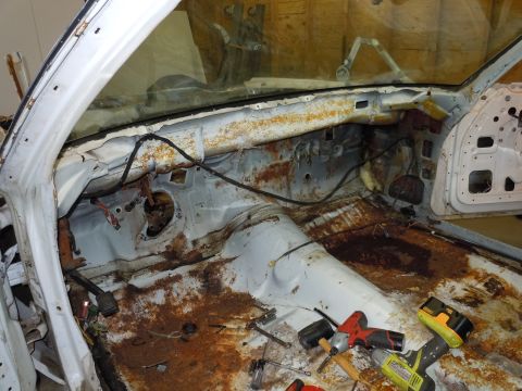 2001 Ford Crown Victoria - The interior of a vehicle is shown stripped down, revealing significant rust damage and exposed components.