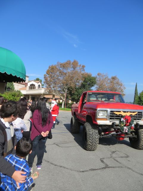 1978 Ford Bronco - Red lifted 1978 Ford Bronco with Christmas decorations drives past onlookers.
