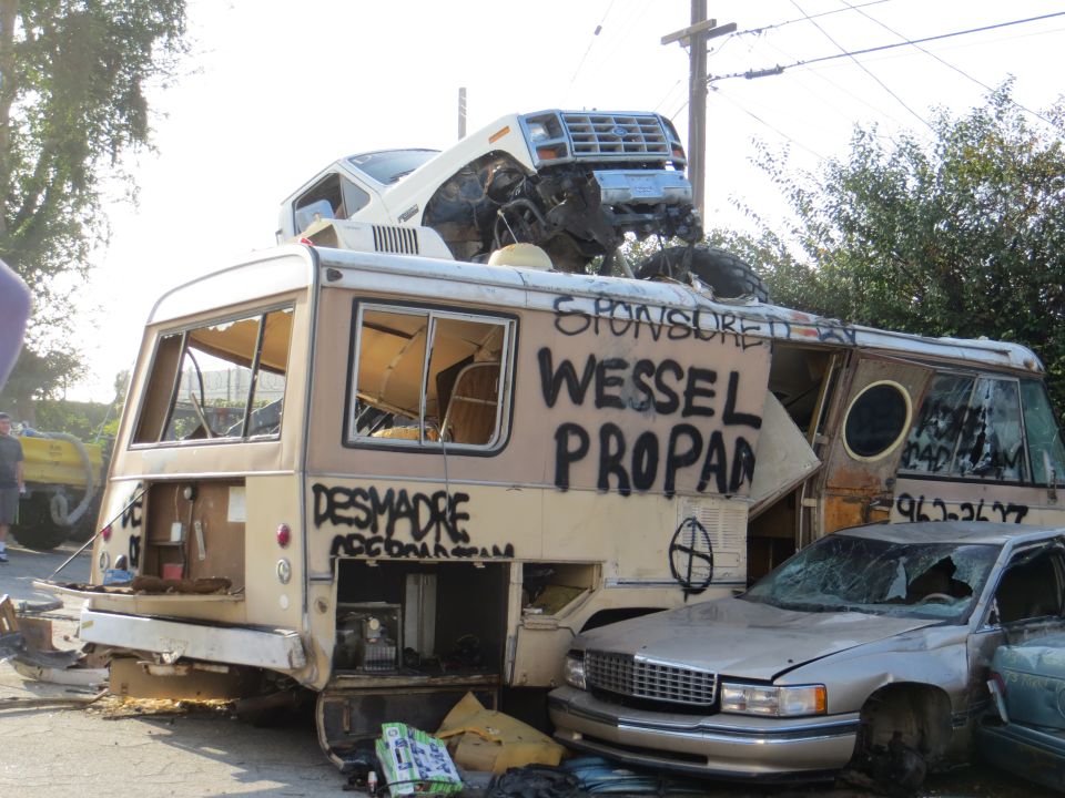 Wrecked RV with a car on top, graffiti on side