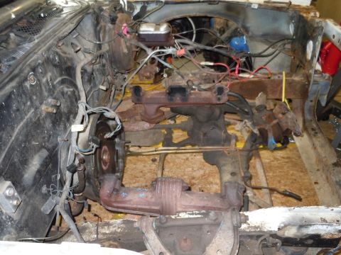 2001 Ford Crown Victoria - The engine bay of a vehicle is shown with various mechanical parts and wiring exposed, indicating a state of disassembly or repair.