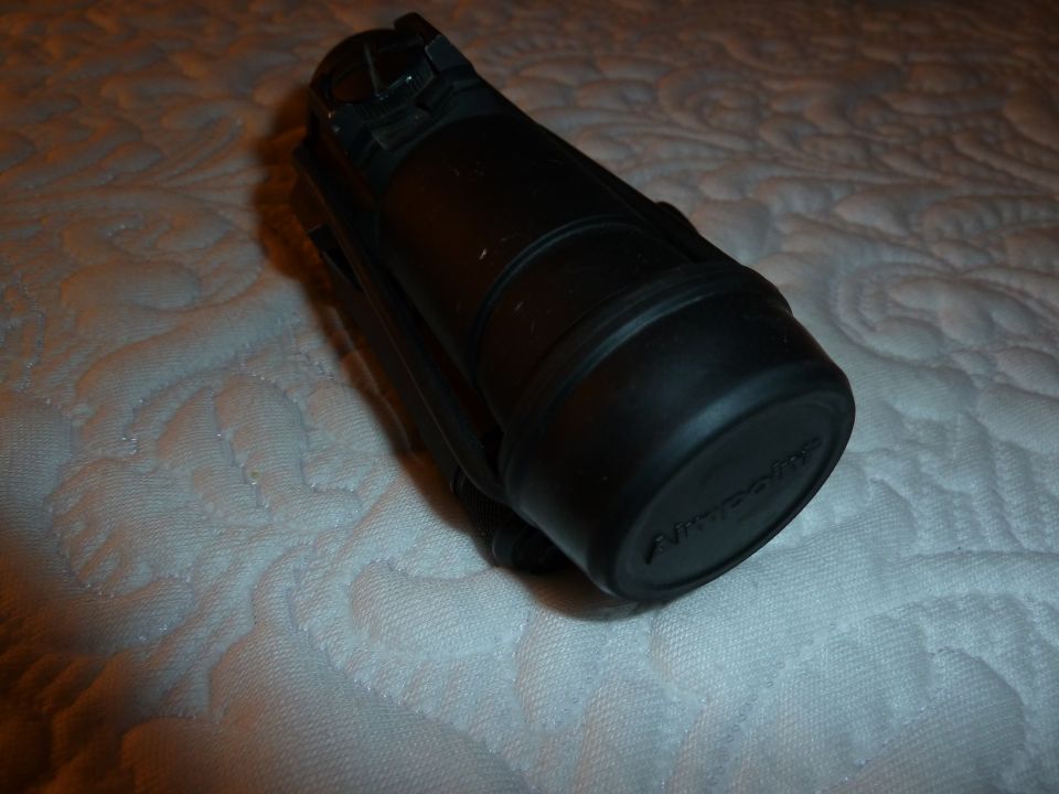 Black flashlight with "Nitecore" text visible on the end cap, resting on a quilted surface