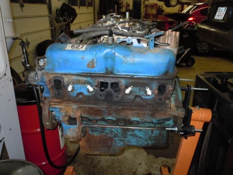 2001 Ford Crown Victoria - Engine block on stand in garage with other vehicles in background.