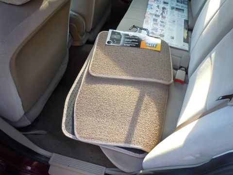 2001 Ford Crown Victoria - New floor mats are placed on the back seat of the car next to a folded newspaper.
